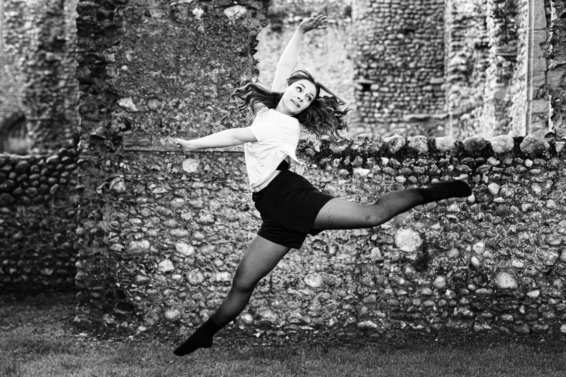 Dancer leaping outside of old ruins. Image is of dancer Kira Rae. Captured by Norfolk dance photographer Fourth Wall Photography