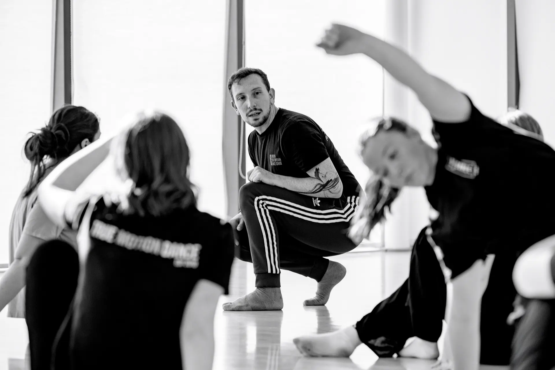 Dance instructor from London Contemporary Dance School leading a workshop with students from True Motion Dance in a bright studio, focusing on technique and movement. Captured by Dance photography specialist, Fourth Wall Photography.