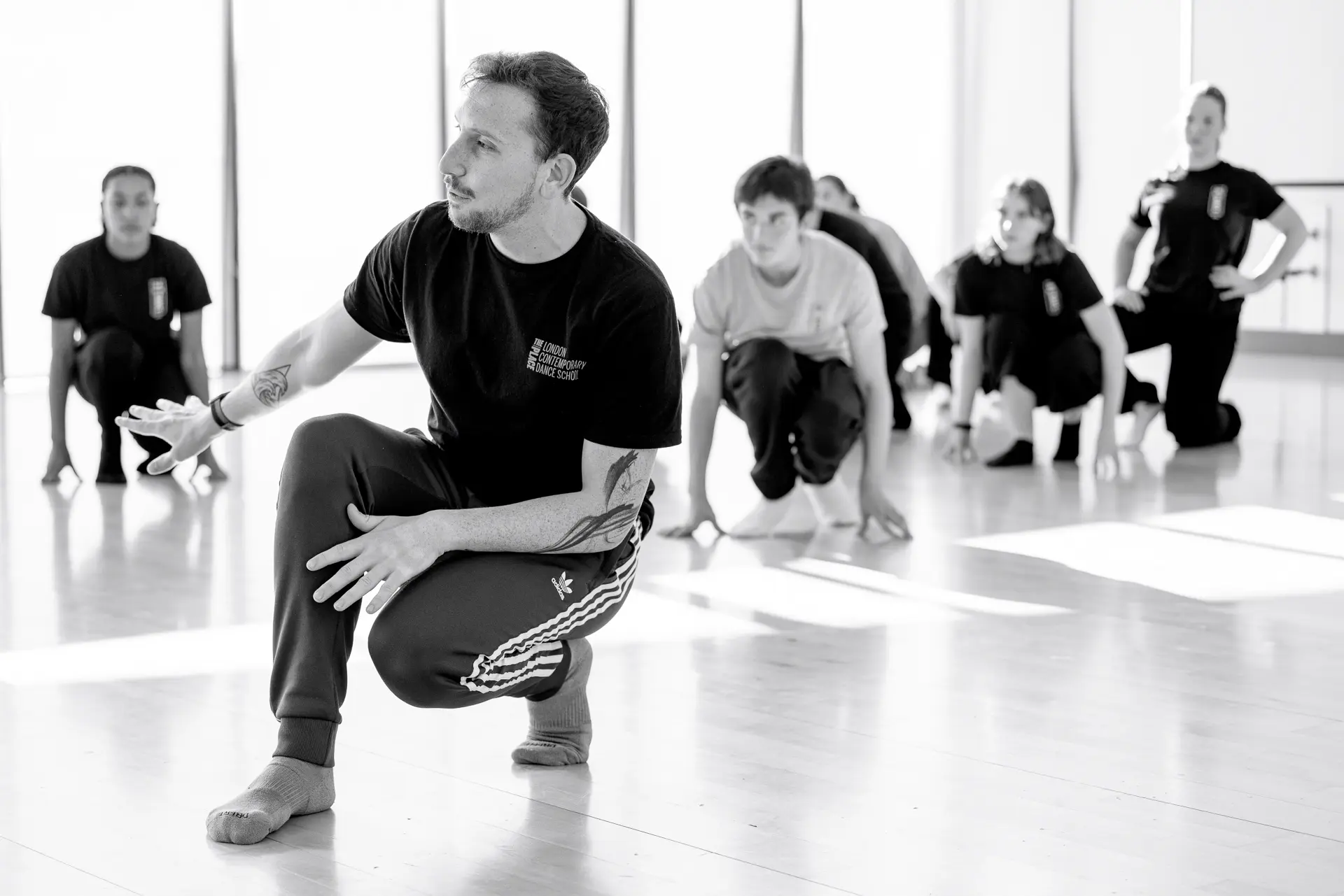 Dance instructor from London Contemporary Dance School leading a workshop with students from True Motion Dance in a bright studio, focusing on technique and movement. Captured by Dance photography specialist, Fourth Wall Photography.