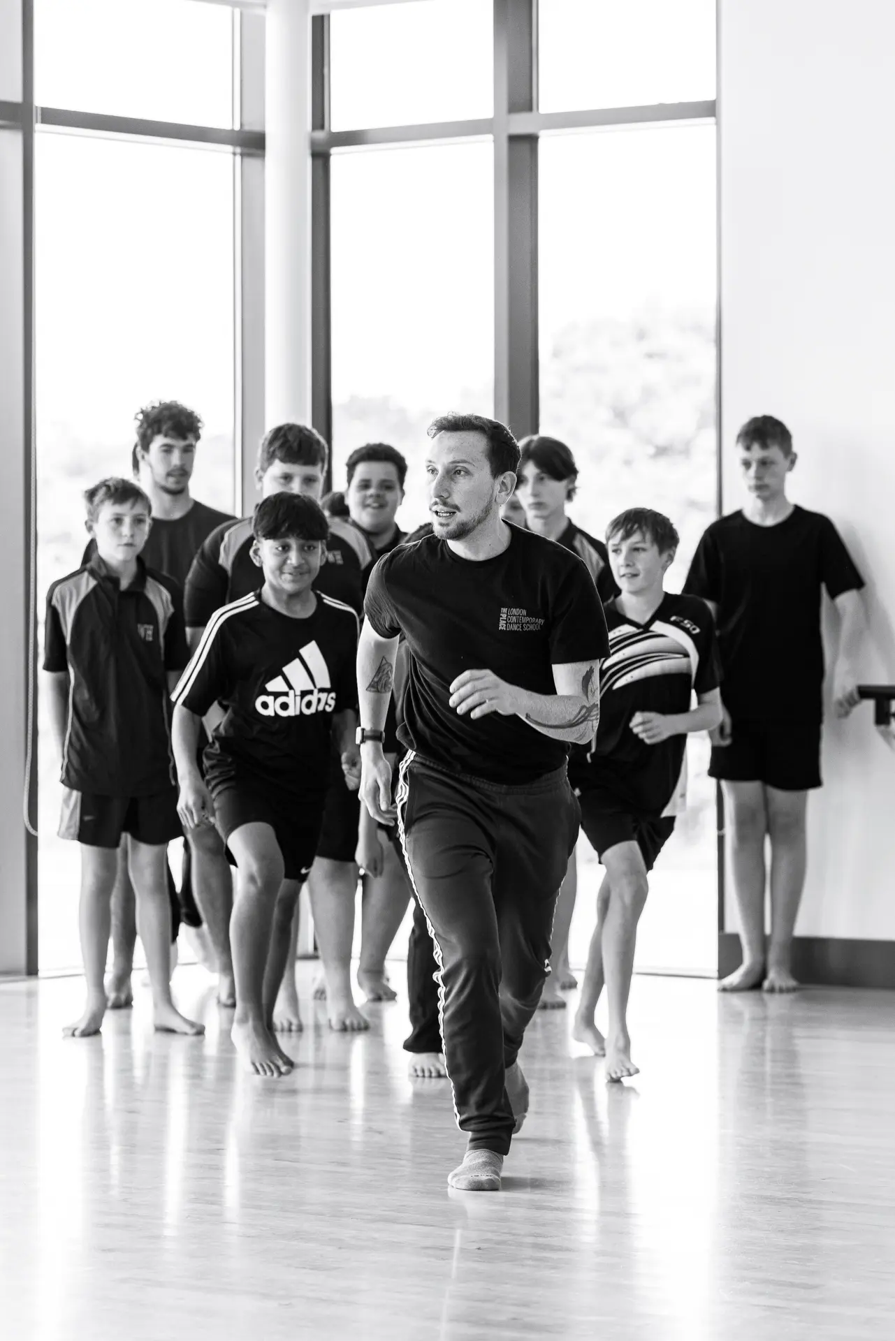 Dance instructor from London Contemporary Dance School leading a workshop with students from True Motion Dance in a bright studio, focusing on technique and movement. Captured by Dance photography specialist, Fourth Wall Photography.