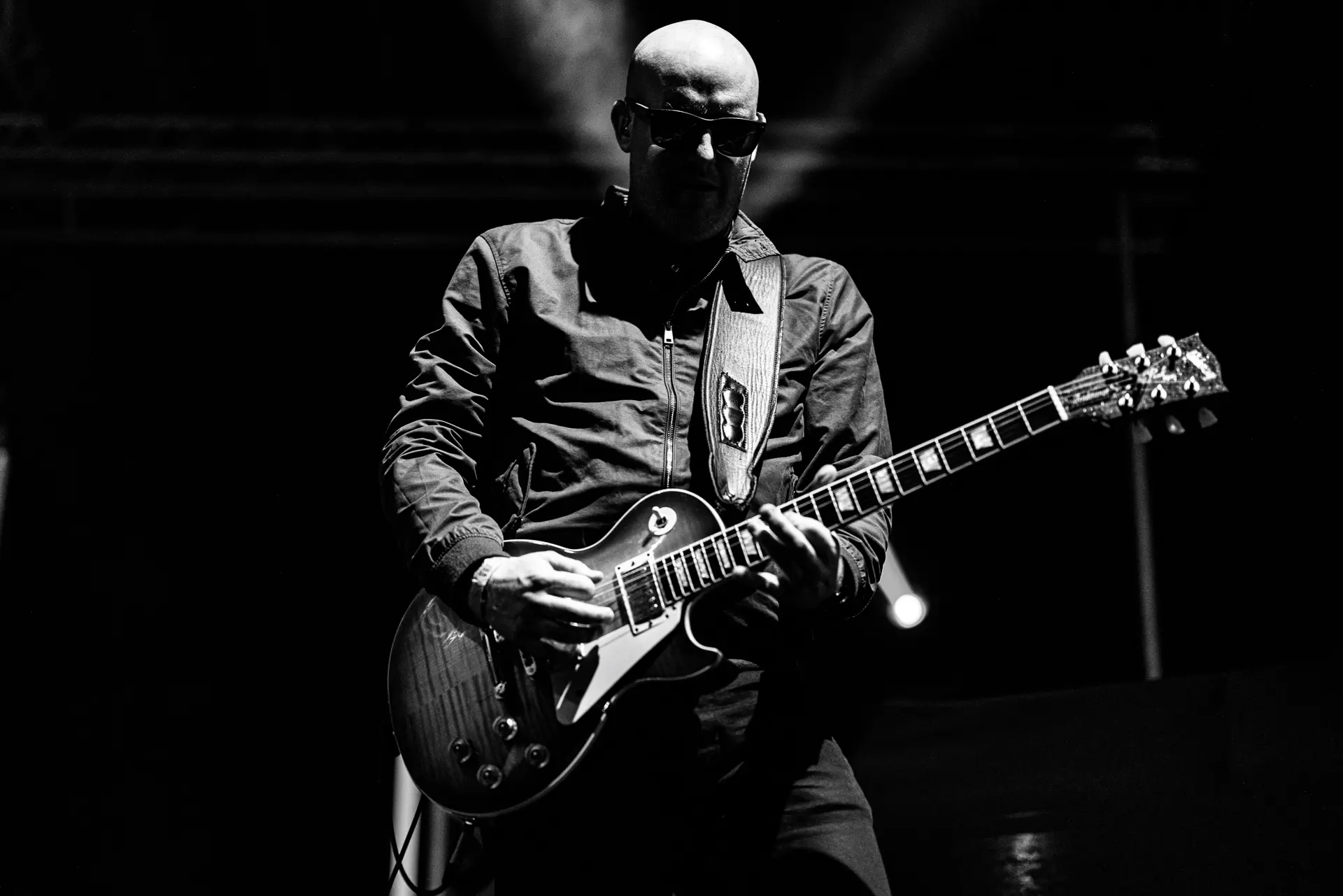 Black and white image of a guitarist from That Britpop Band performing intensely on stage at the Legends Music Festival in Cromer. Captured by Live Music photography specialist, Fourth Wall Photography.