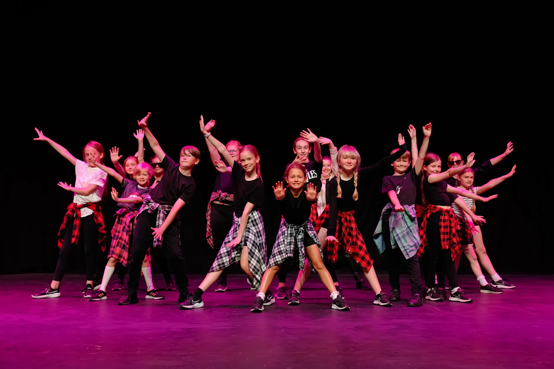 Young dancers performing a routine at the Schools Dance Festival at the Marina Theatre Lowestoft. Captured mid‑movement on stage with vibrant lighting. Captured by Dance photography specialist, Fourth Wall Photography.
