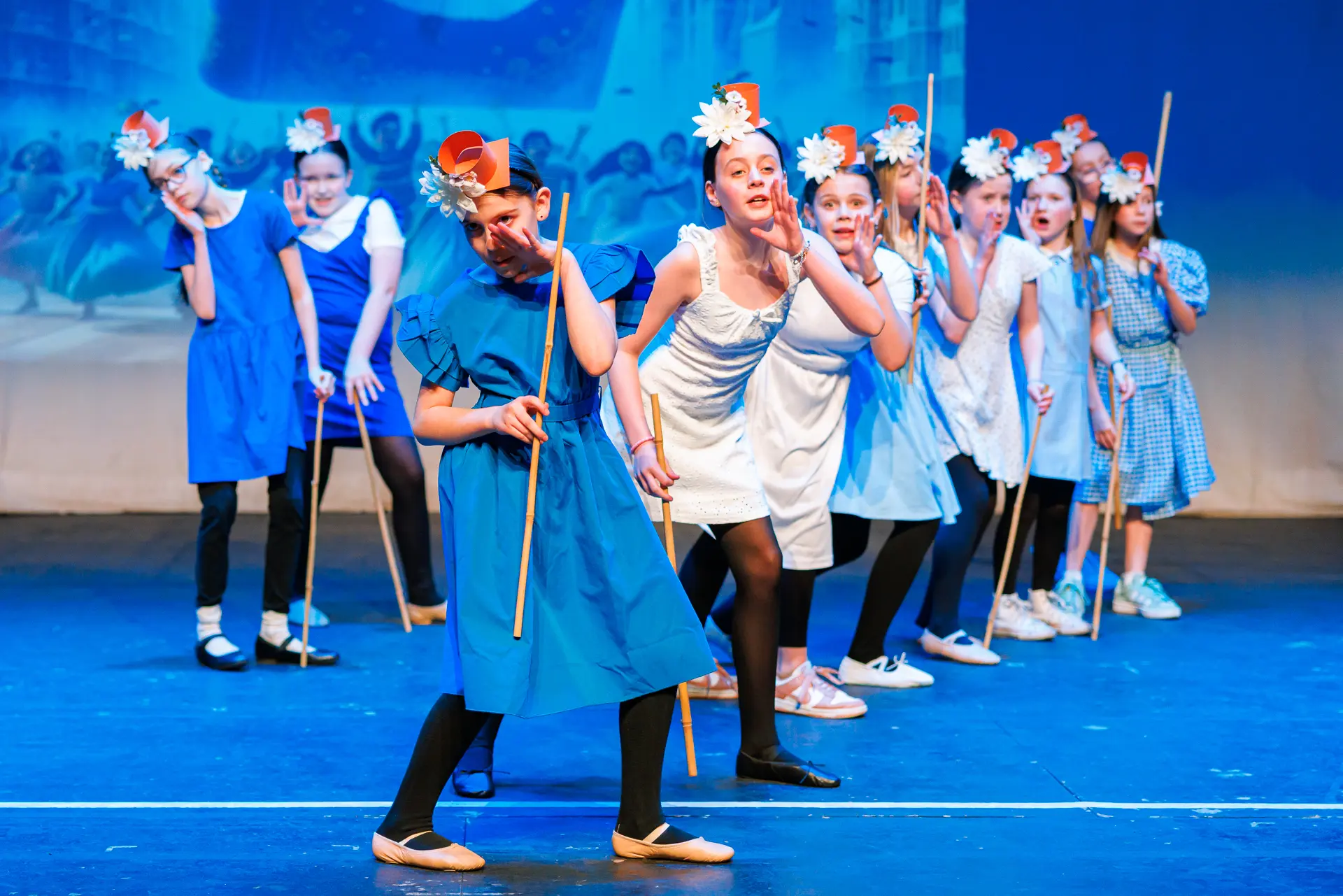 Young dancers performing a musical theatre routine at the Schools Dance Festival at the Marina Theatre Lowestoft. Captured mid‑movement on stage with vibrant lighting. Captured by Dance photography specialist, Fourth Wall Photography.