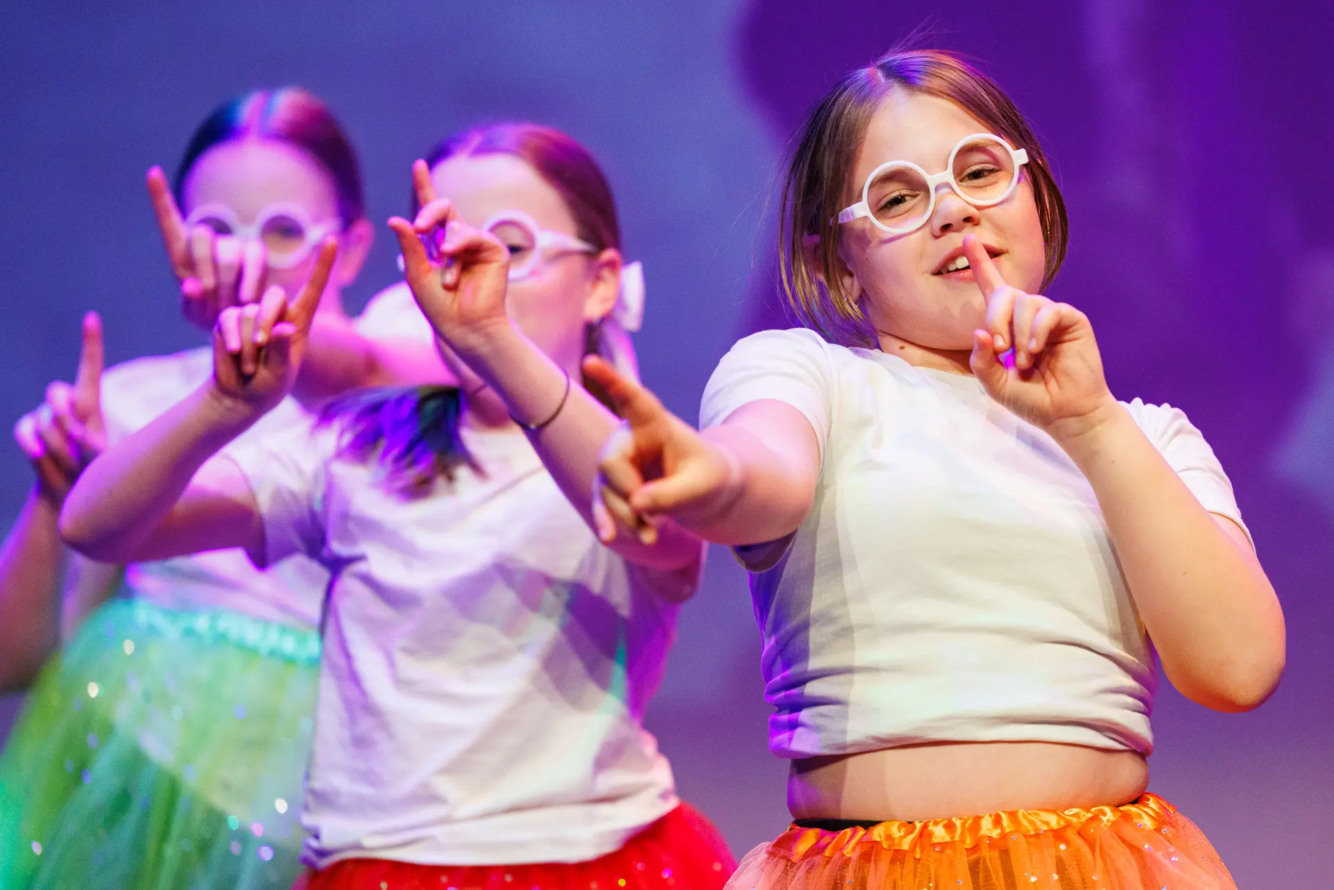 Young dancers performing a musical theatre routine at the Schools Dance Festival at the Marina Theatre Lowestoft. Captured mid‑movement on stage with vibrant lighting. Captured by Dance photography specialist, Fourth Wall Photography.
