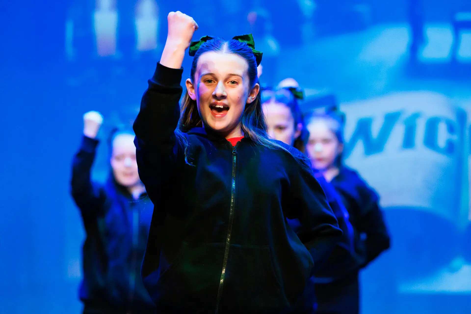 Young dancers performing a street dance routine at the Schools Dance Festival at the Marina Theatre Lowestoft. Captured mid‑movement on stage with vibrant lighting. Captured by Dance photography specialist, Fourth Wall Photography.