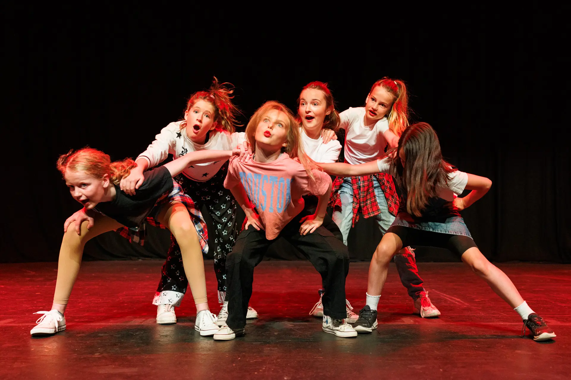 Young dancers performing a routine at the Schools Dance Festival at the Marina Theatre Lowestoft. Captured mid‑movement on stage with vibrant lighting. Captured by Dance photography specialist, Fourth Wall Photography.