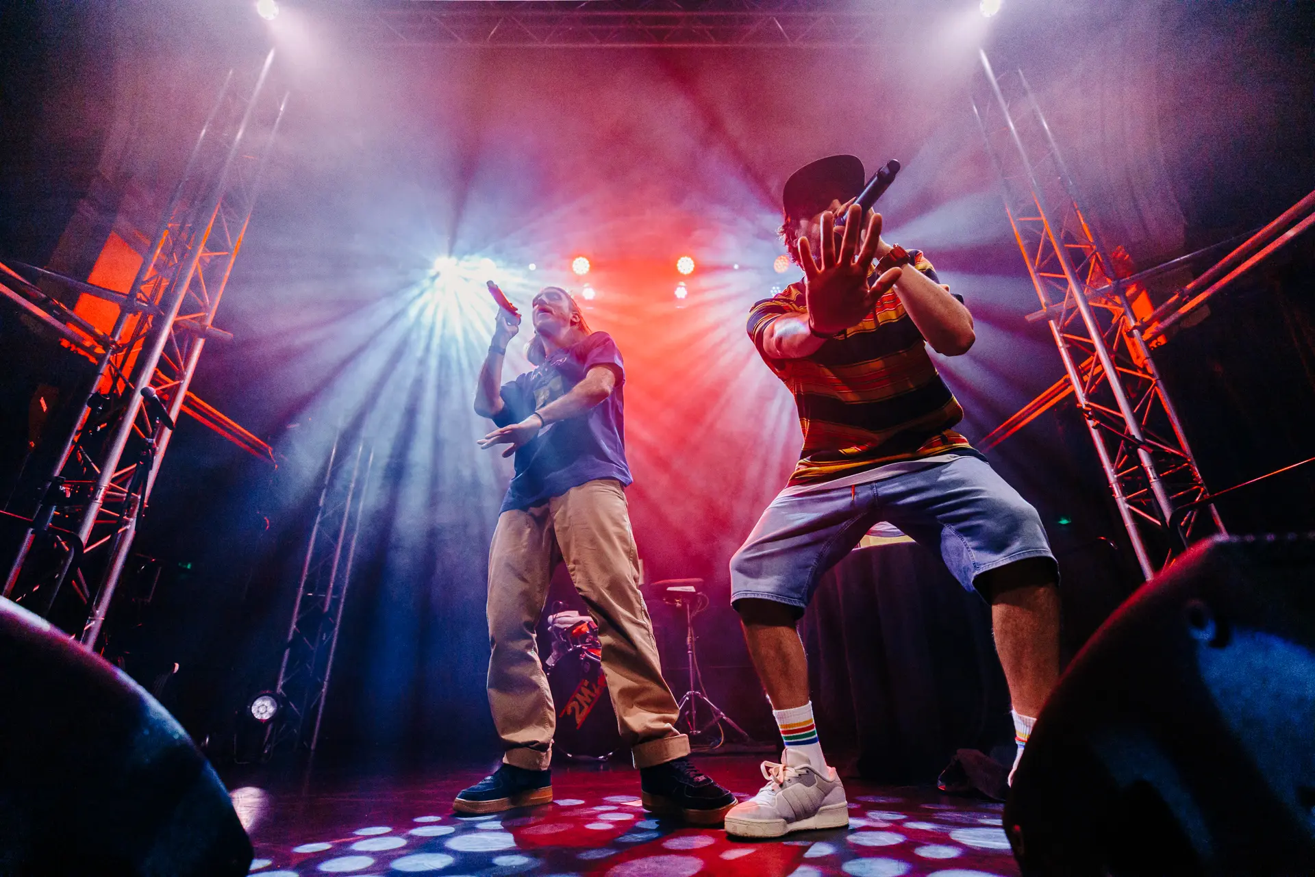 Rap duo Too Many T's performing live on stage at Norwich Arts Centre, rapping into microphones under stage lights and smoke. Captured by Live Music photography specialist, Fourth Wall Photography.